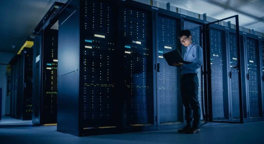 person using laptop in server room